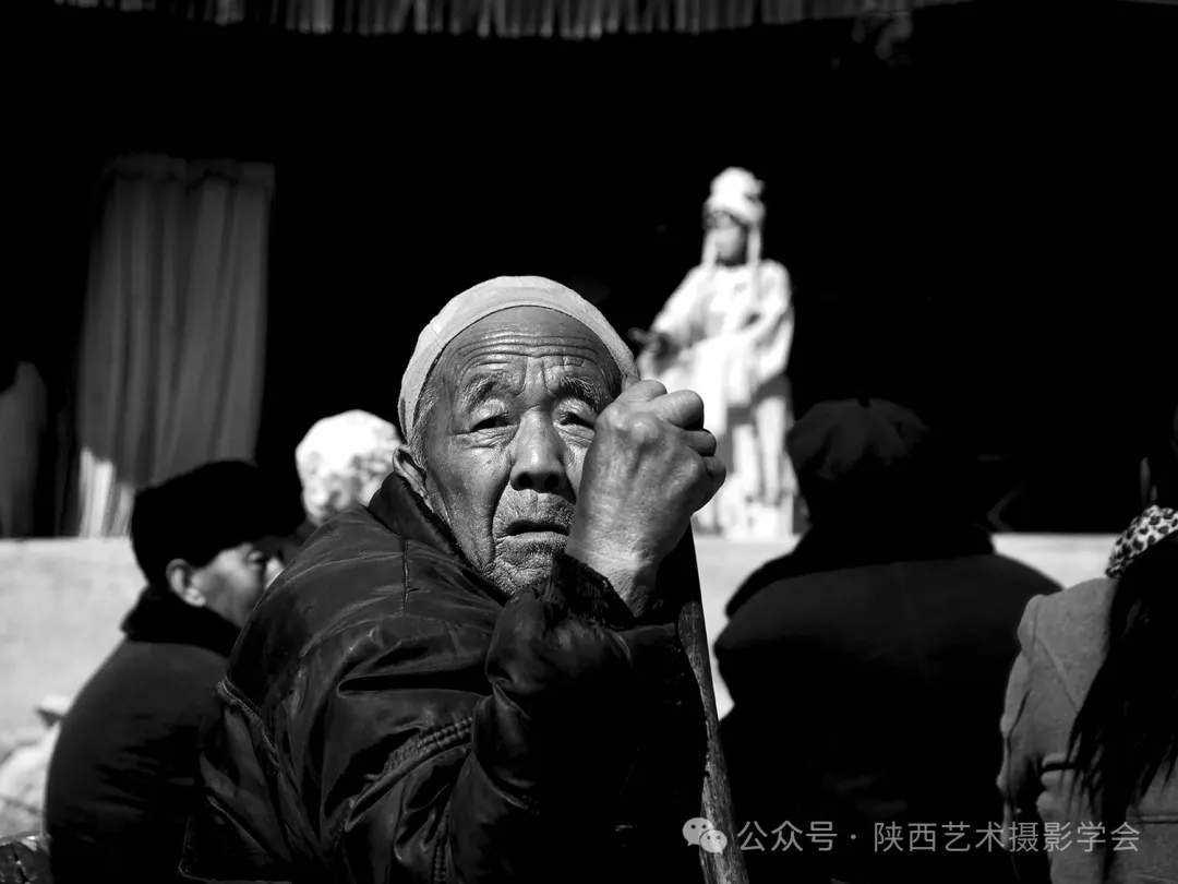  2016年3月13日，延川县李家千村庙会上，老人也早早就坐在了戏台下，台上唱着“古今”，老人的蓦然回首，说不清道不尽的沧桑，仿佛脸上每道沟壑般的皱纹都是一段岁月的记忆。
